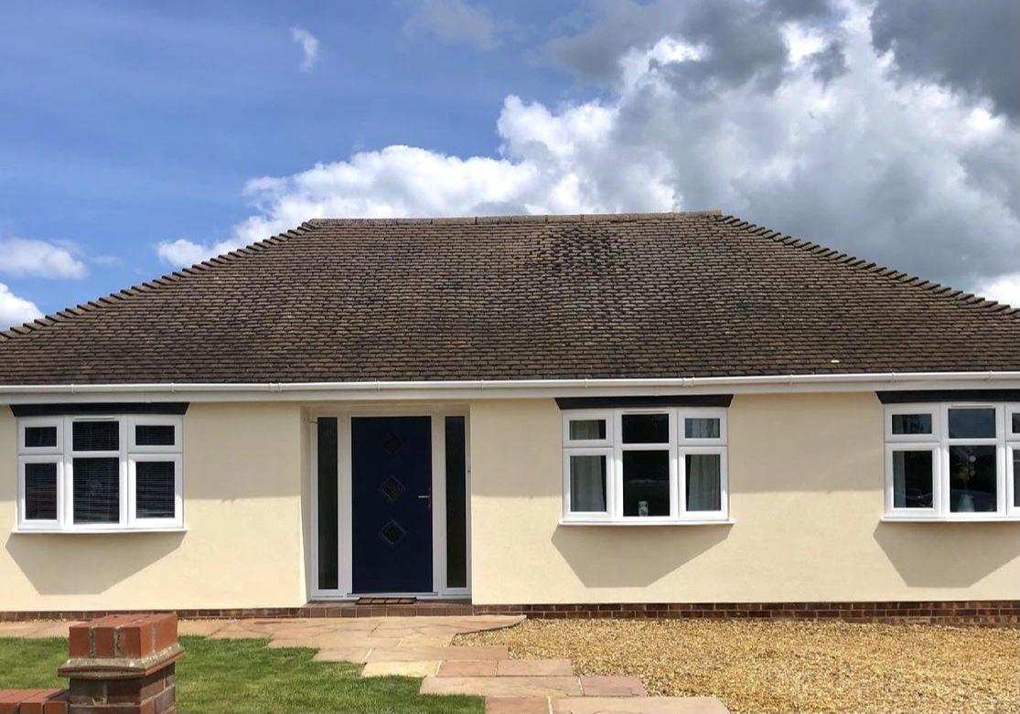 Bungalow finished in cream render with a navy front door